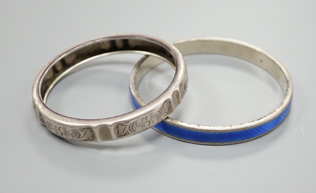 A 1920's silver and blue enamel bangle and an engraved white metal bangle.